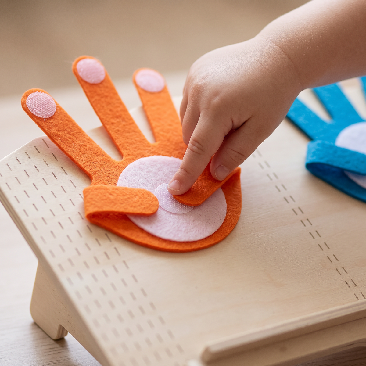 Close up of a small hand pressing an orange felt finger onto the palm